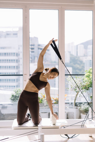 Reformer Pilates side bend exercise on the platform to improve lateral flexibility and oblique strength.