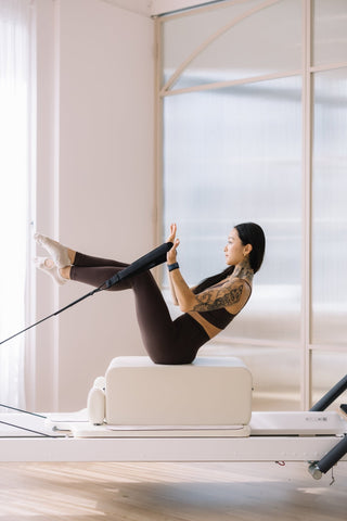 V-sit pilates reformer exercise on the long box using straps for core stability and balance.